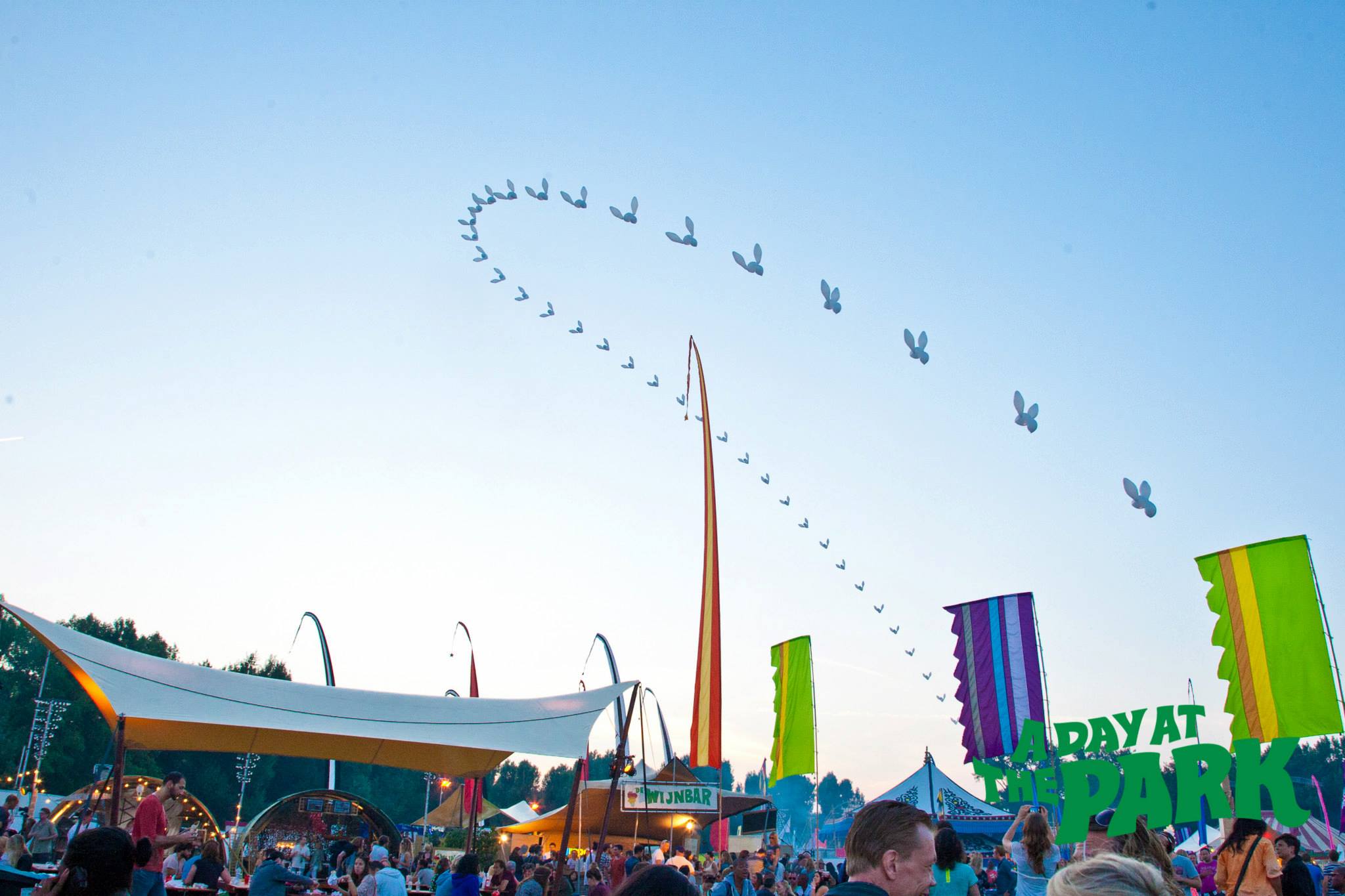 LED balloon chains and floating characters above festival crowd — High Lines